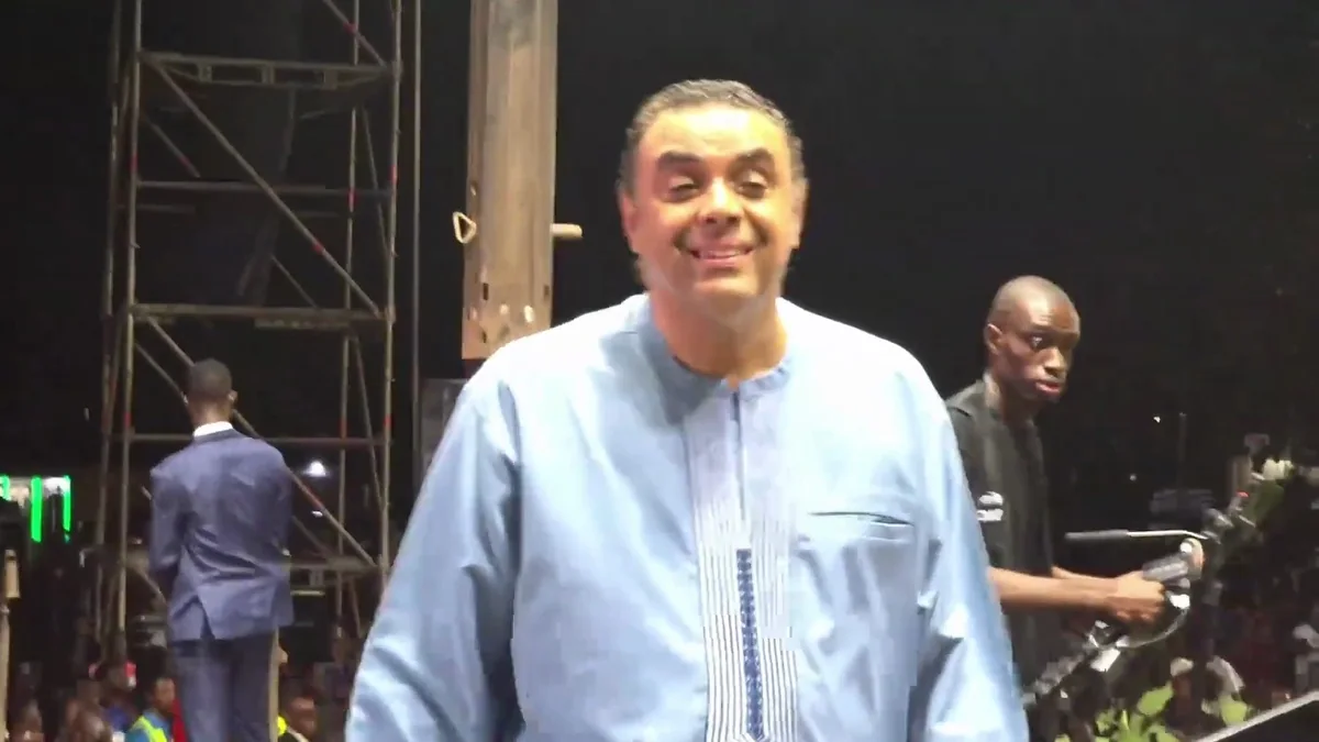 Bishop Dag Heward-Mills smiling broadly on a crusade stage, pastors and camera crew around him.